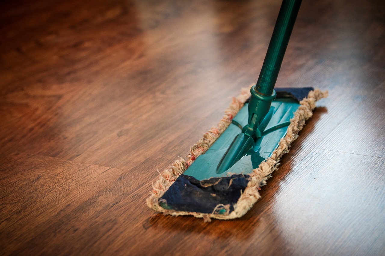 Professional home cleaning service using a mop on hardwood floors, ensuring a spotless and well-maintained living space