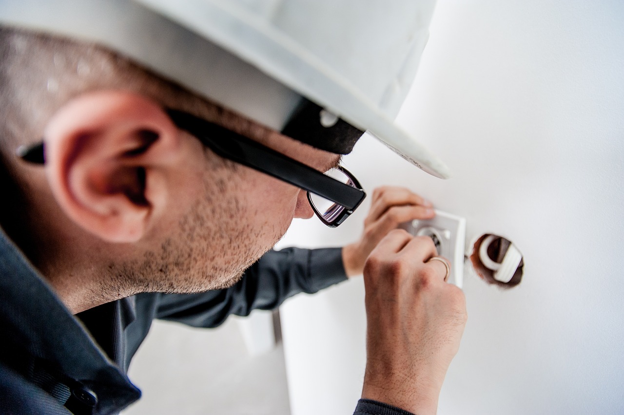 Professional electrician installing or repairing an electrical outlet, providing reliable electrical services for safe and efficient home wiring